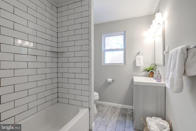 bathroom with vanity, wood finished floors, baseboards, bathtub / shower combination, and toilet