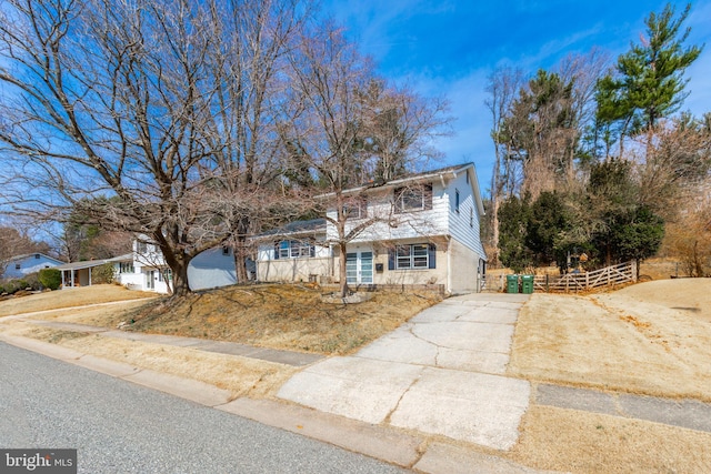 view of front of home with brick siding, concrete driveway, and fence