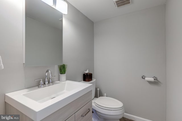 half bath featuring visible vents, toilet, and vanity