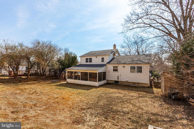 rear view of property featuring fence, a lawn, a chimney, and a sunroom