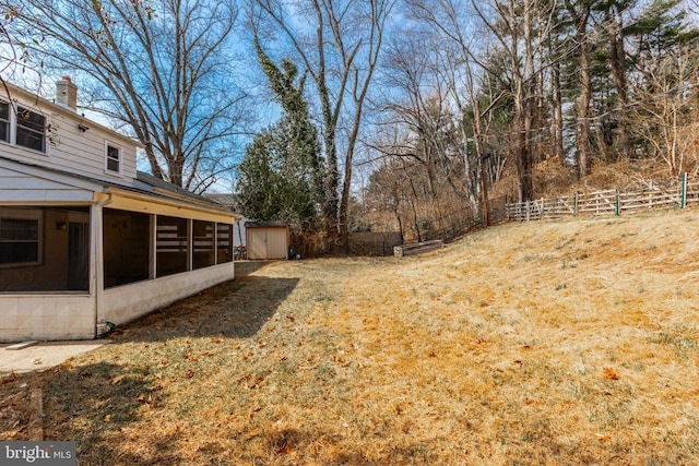 view of yard featuring a storage shed, an outdoor structure, fence, and a sunroom