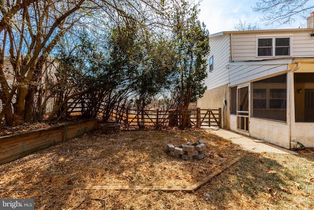 view of yard featuring an outdoor fire pit, a sunroom, and fence