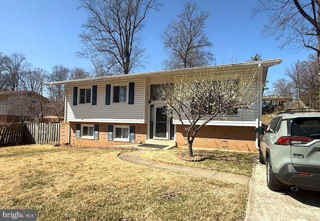 bi-level home with brick siding, a front yard, and fence