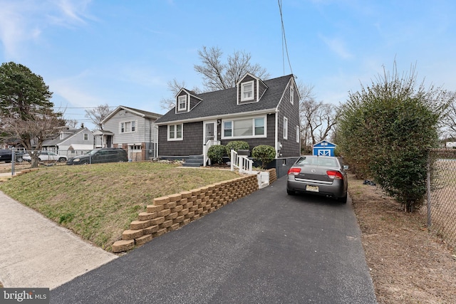 view of front of home with a front yard, fence, an outbuilding, and driveway