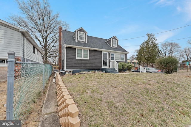 cape cod-style house featuring a chimney, a shingled roof, a front lawn, and fence