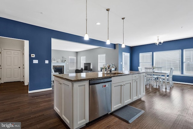 kitchen featuring a fireplace, dark wood finished floors, stainless steel dishwasher, white cabinets, and a sink