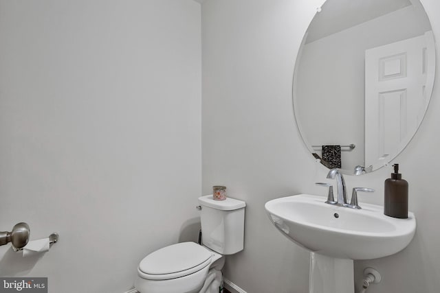 half bathroom featuring a sink, toilet, and baseboards