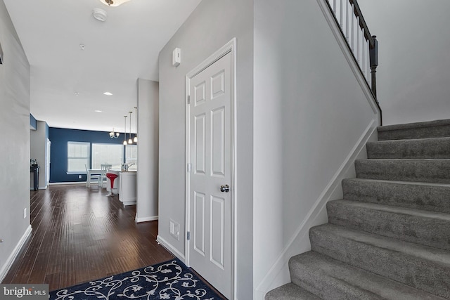 staircase featuring baseboards, a chandelier, and wood finished floors