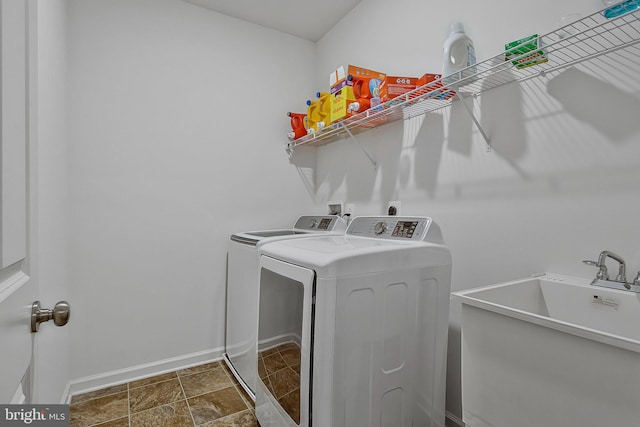 laundry area with washing machine and dryer, laundry area, a sink, and baseboards