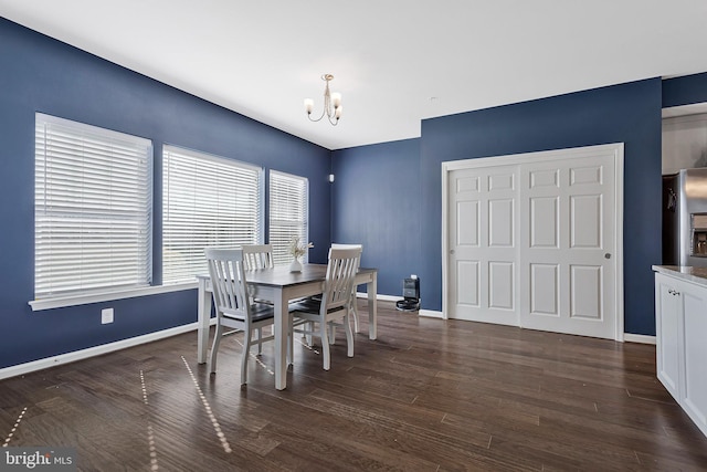 dining area with dark wood-style flooring, a notable chandelier, and baseboards