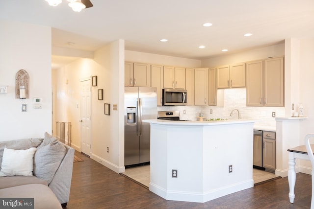 kitchen featuring tasteful backsplash, stainless steel appliances, light countertops, and wood finished floors