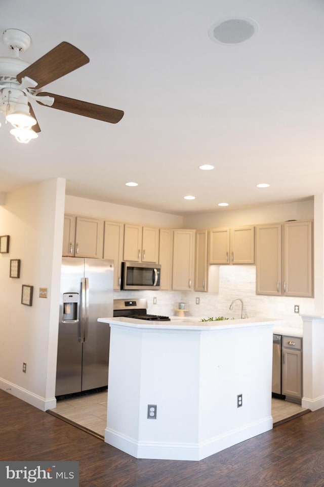 kitchen with wood finished floors, recessed lighting, light countertops, appliances with stainless steel finishes, and tasteful backsplash