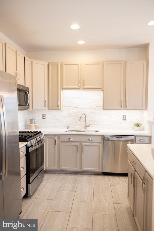 kitchen featuring tasteful backsplash, appliances with stainless steel finishes, light countertops, and a sink