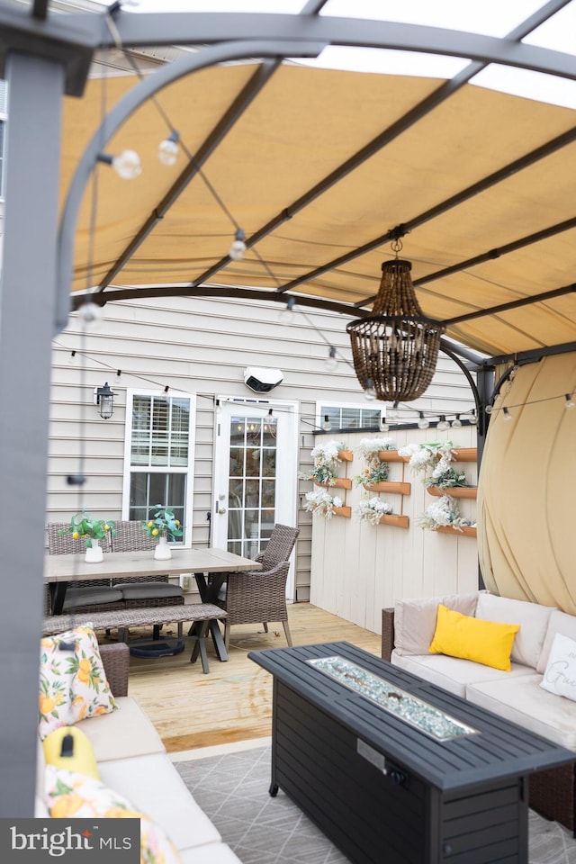 wooden terrace with an outdoor living space with a fire pit and a patio area