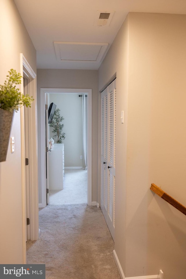 corridor with attic access, carpet flooring, baseboards, and visible vents