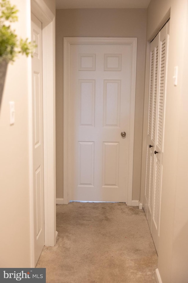 hall featuring baseboards and light carpet