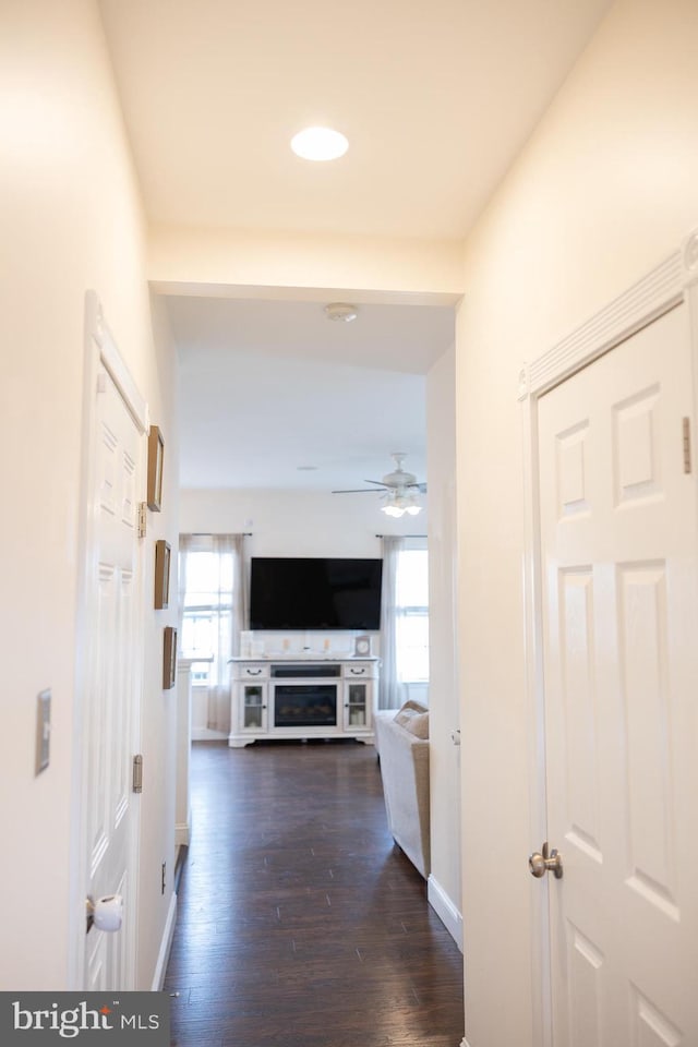 corridor featuring baseboards and dark wood finished floors