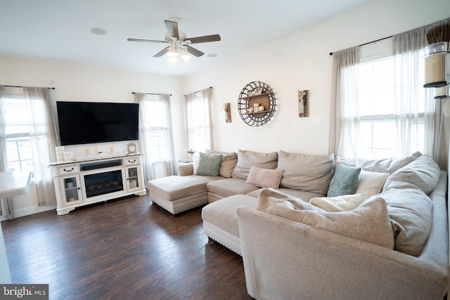 living area with dark wood-type flooring, a wealth of natural light, and ceiling fan