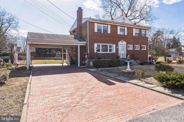 view of front of home featuring brick siding, a chimney, and decorative driveway