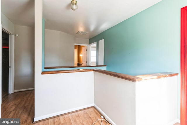 hallway with visible vents, baseboards, and wood finished floors