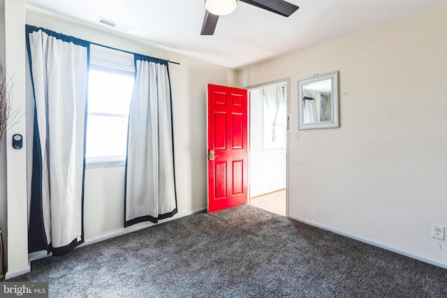 carpeted empty room with a ceiling fan, visible vents, and baseboards