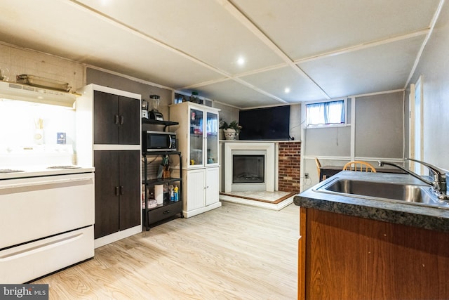 kitchen with stainless steel microwave, light wood-style flooring, a fireplace, white electric range oven, and a sink