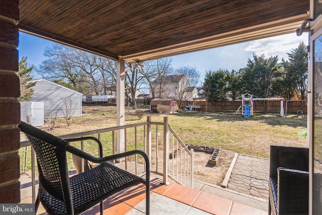 view of patio / terrace featuring a fenced backyard, a storage unit, a playground, and an outdoor structure