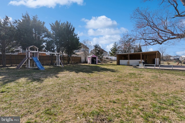 view of yard with an outbuilding, a playground, and fence