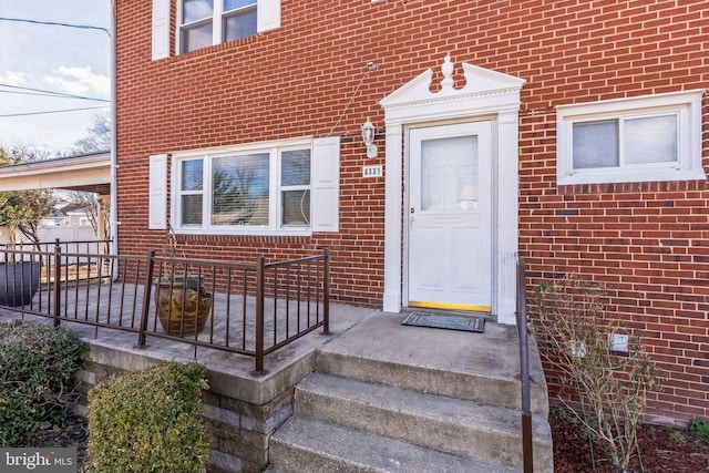 entrance to property featuring fence and brick siding