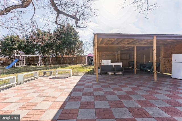 view of patio with an outdoor structure, a fenced backyard, and a playground