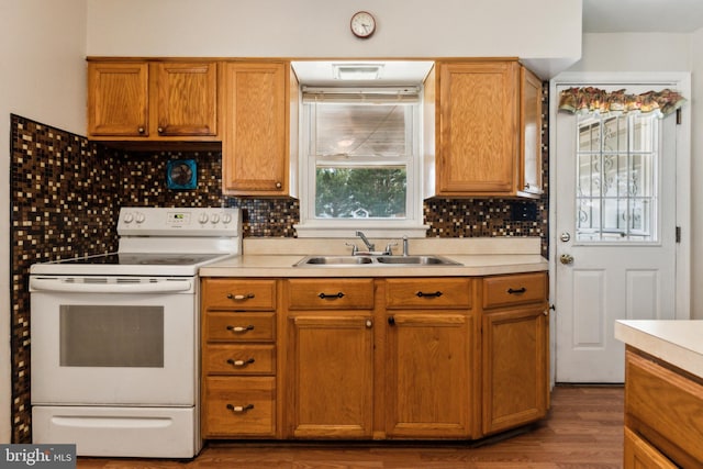 kitchen featuring decorative backsplash, light countertops, electric stove, and a sink