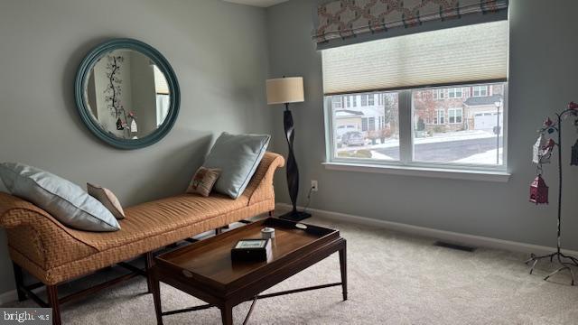 living area featuring visible vents, baseboards, and light colored carpet