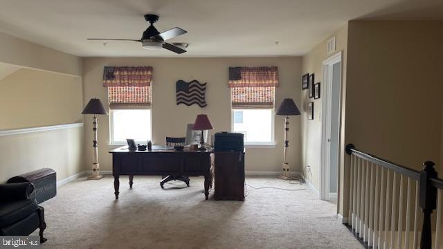 carpeted office space with visible vents, baseboards, and a ceiling fan