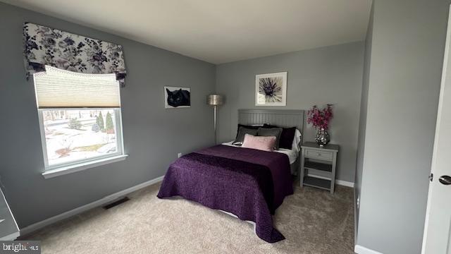 carpeted bedroom featuring visible vents and baseboards