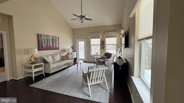 living area with dark wood finished floors, a ceiling fan, baseboards, and high vaulted ceiling