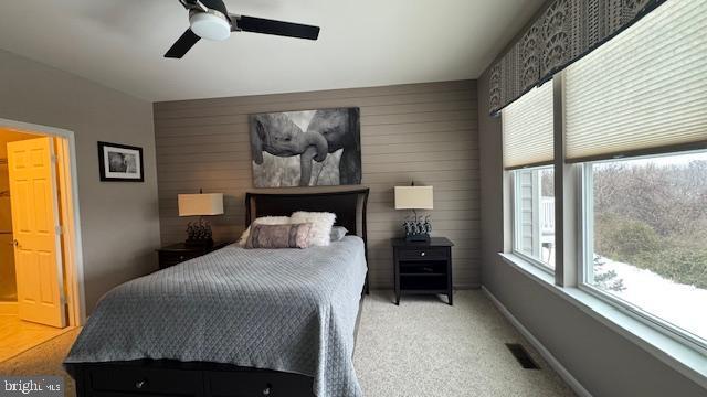 carpeted bedroom with a ceiling fan, visible vents, and baseboards