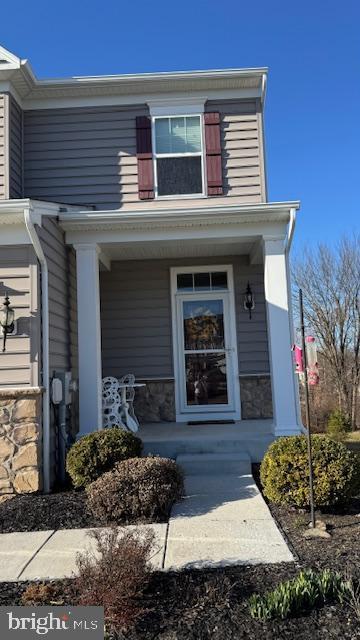 property entrance featuring stone siding and covered porch