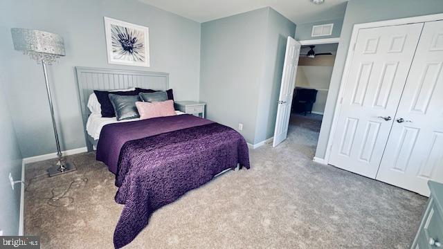 carpeted bedroom with visible vents, baseboards, and a closet