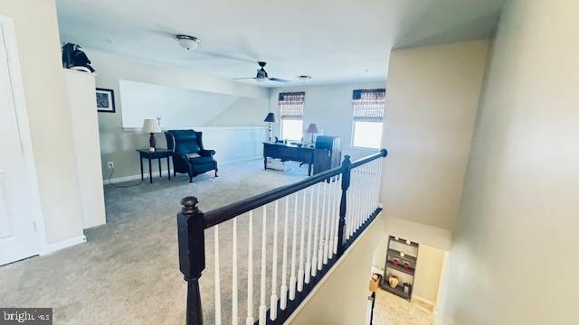 corridor featuring an upstairs landing, baseboards, and carpet floors