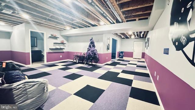 finished basement with tile patterned floors and a wainscoted wall