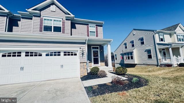 view of front of house featuring an attached garage, a front lawn, a porch, and driveway