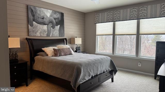 carpeted bedroom featuring baseboards and wood walls