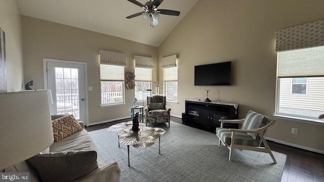 living room with ceiling fan, baseboards, high vaulted ceiling, and wood finished floors