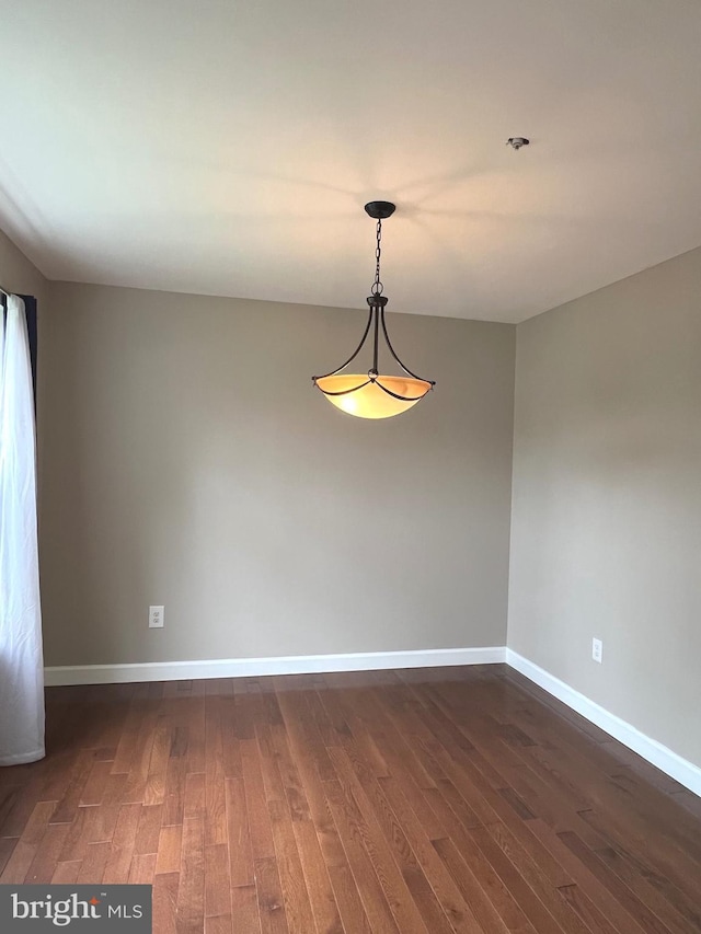 spare room featuring dark wood-style floors and baseboards
