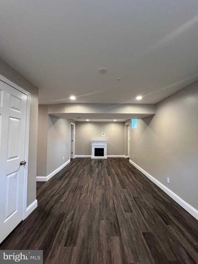 finished below grade area with baseboards, recessed lighting, a fireplace, and dark wood finished floors