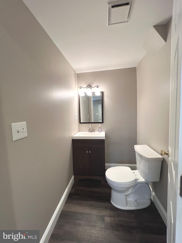 half bath featuring visible vents, baseboards, toilet, and wood finished floors