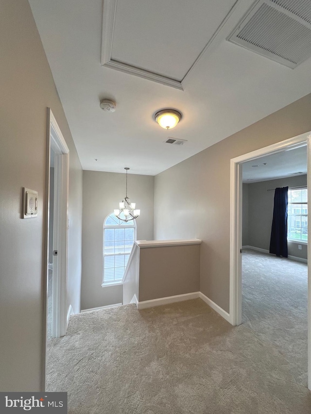 hall with visible vents, baseboards, carpet flooring, and a notable chandelier