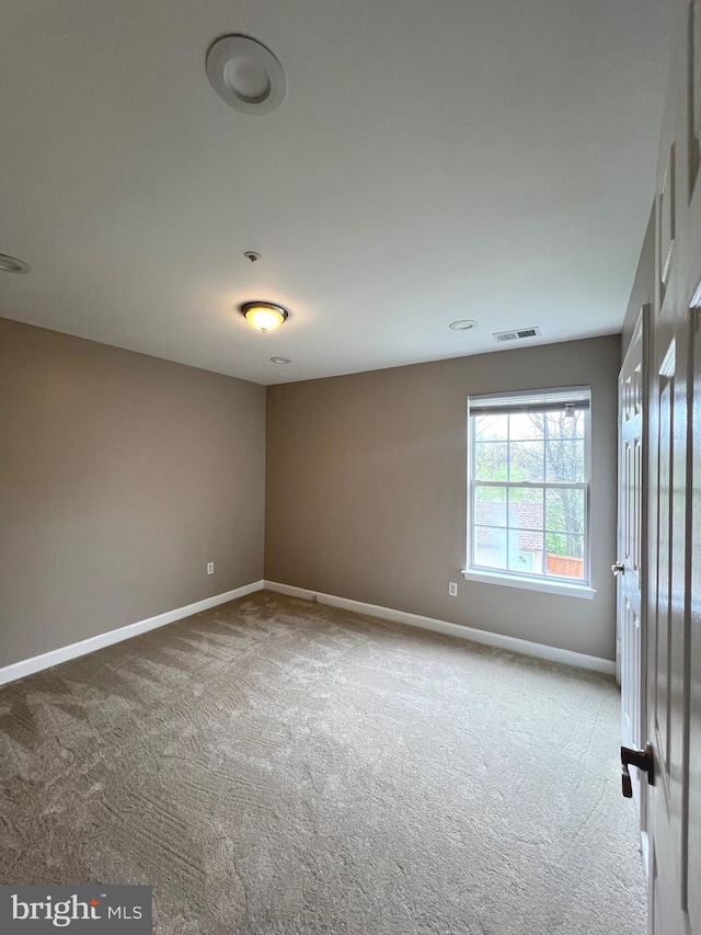 carpeted empty room with visible vents and baseboards