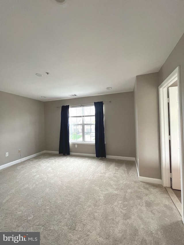 empty room with baseboards and light colored carpet