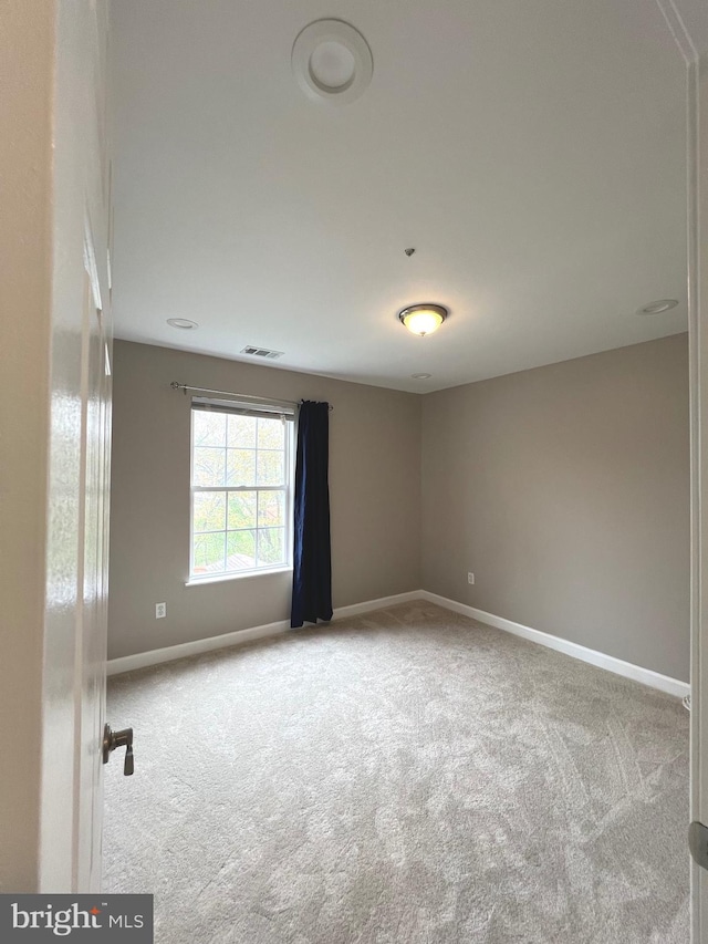 carpeted spare room featuring visible vents and baseboards